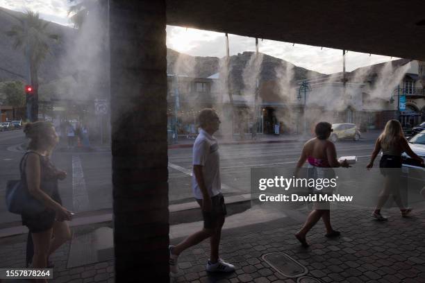 People walk under sidewalk water misters as record-breaking heatwaves occur across the nation on July 22, 2023 in Palm Springs, California. Extreme...