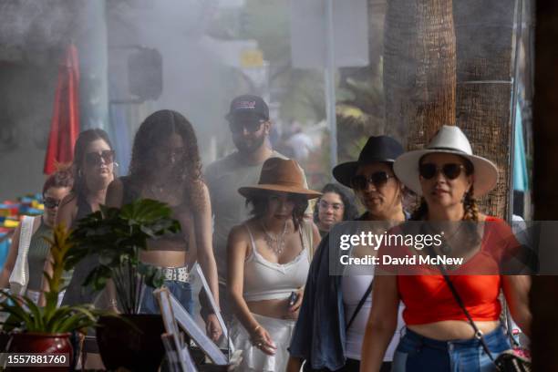 People walk by water misters that line downtown sidewalks and restaurants as record-breaking heatwaves occur across the nation on July 22, 2023 in...