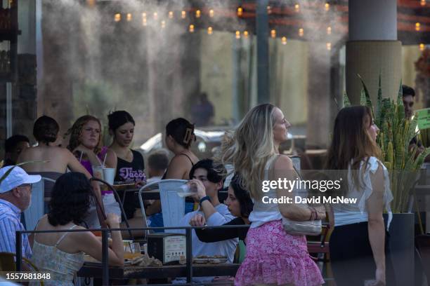 People walk by water misters that line downtown sidewalks and restaurants as record-breaking heatwaves occur across the nation on July 22, 2023 in...