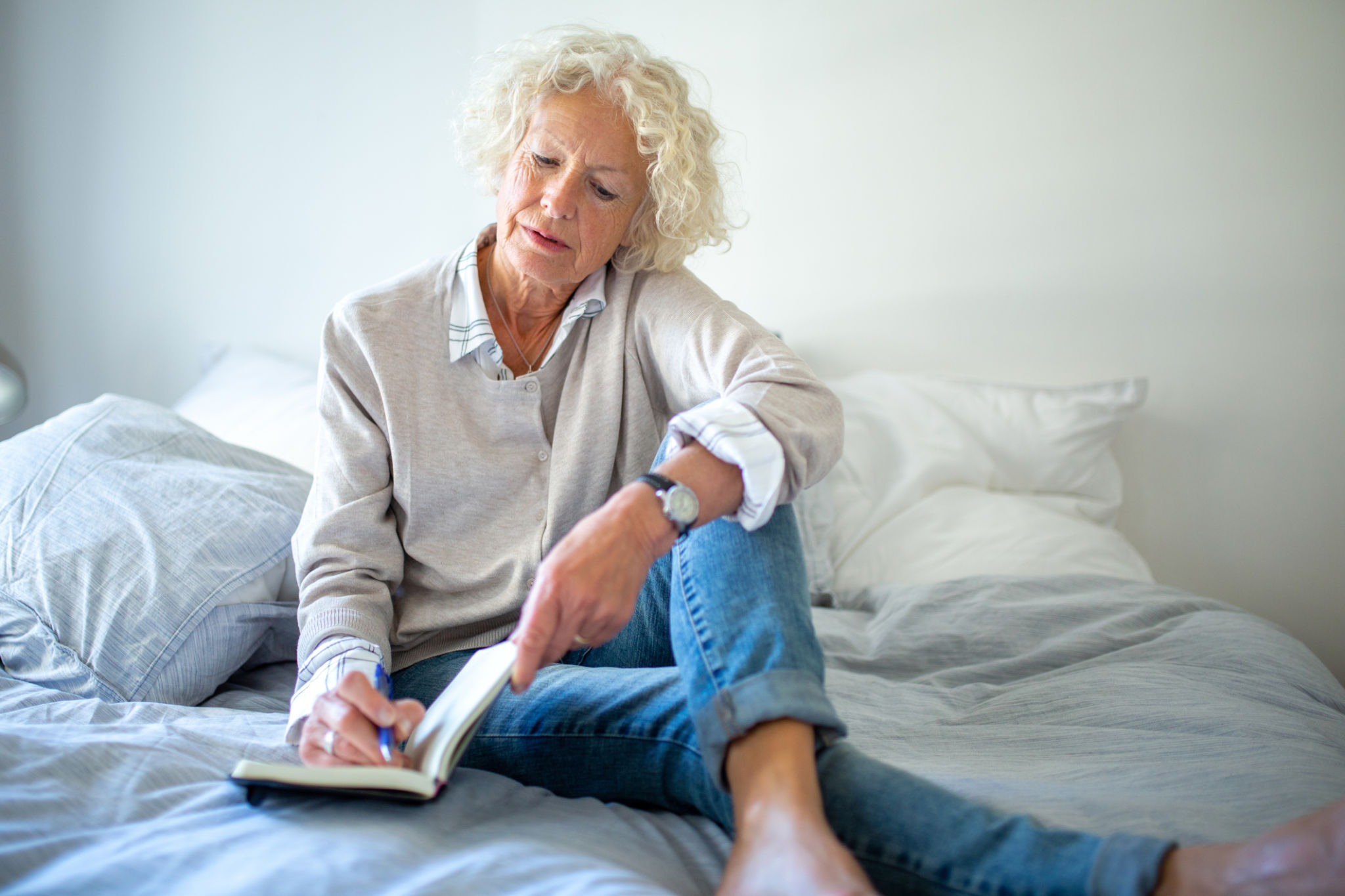 elderly woman relaxing in bed at home with book and pen elderly woman relaxing in bed at home with book and pen