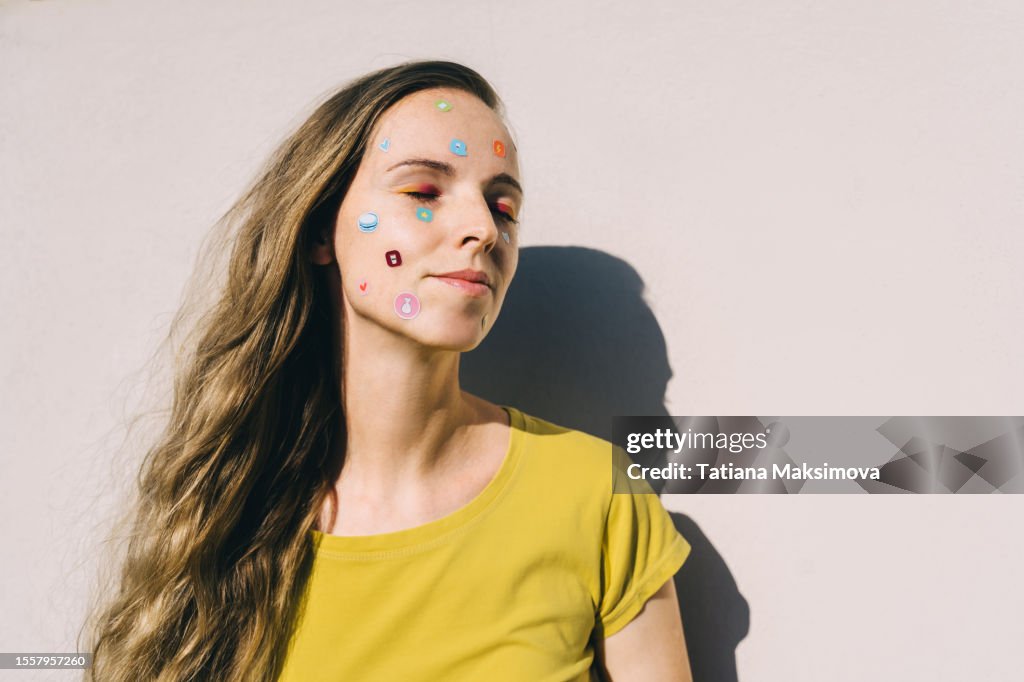 Close-up of an adult woman with bright make-up and cheerful stickers on her face.