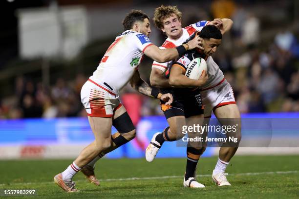 Jack Bird and Toby Couchman of the Dragons make a tackle on Brandon Wakeham of the Tigers during the round 21 NRL match between St George Illawarra...