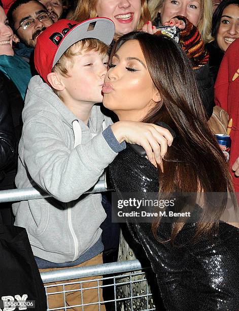 Kim Kardashian kisses a young fan at the Kardashian Kollection launch for Dorothy Perkins at Aqua on November 8, 2012 in London, England.