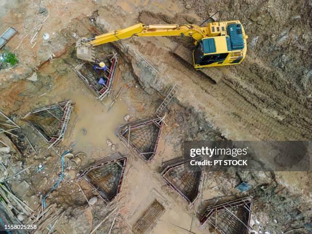 aerial view a construction site excavator is helping to lift steel for workers to assemble into the construction foundation. - väg och vattenbyggnadsingenjör bildbanksfoton och bilder