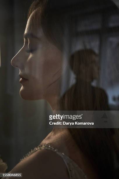 a closeup portrait of a young beautiful asian woman in profile with her eyes closed, against the background of a woman's head in the glass reflects the silhouette of a man, the concept of long-distance relationships, dreams of the future, of a family. - long distance relationship stockfoto's en -beelden