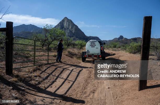 Steve Paz, a volunteer with the Arizona Game and Fish Department, holds open a fence to allow a truck carrying water to access a road to wildlife...