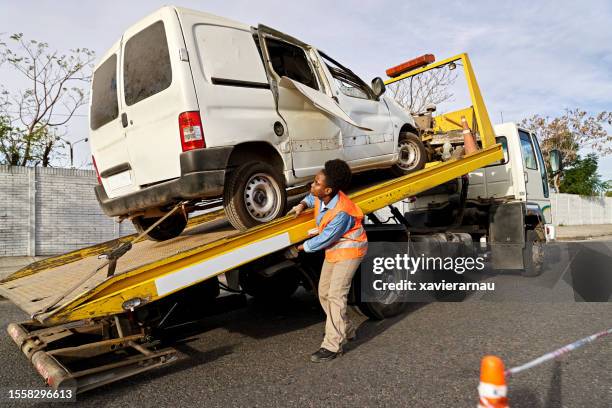 towing service removing damaged van from crash site - car towing stock pictures, royalty-free photos & images