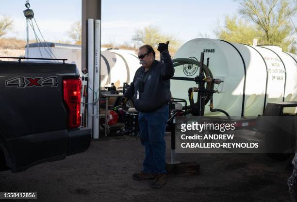 Steve Paz, a volunteer with the Arizona Game and Fish Department helps connect a pickup truck to a water tank in Tucson, Arizona on July 27, 2023....