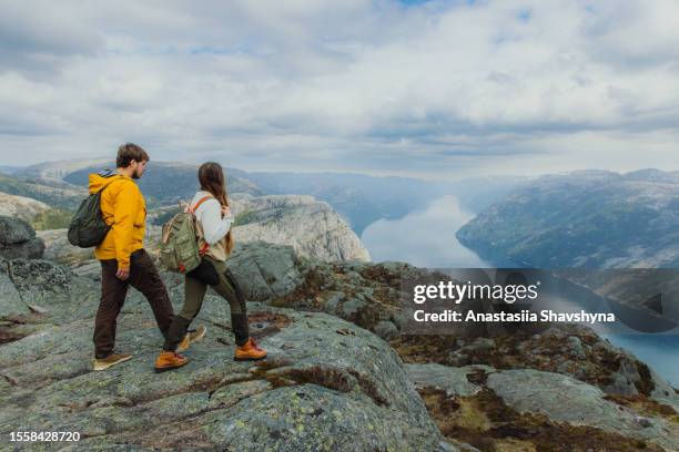 donna e uomo backpackers contemplando vista panoramica di lysefjord dall'alto in norvegia - nord europeo foto e immagini stock