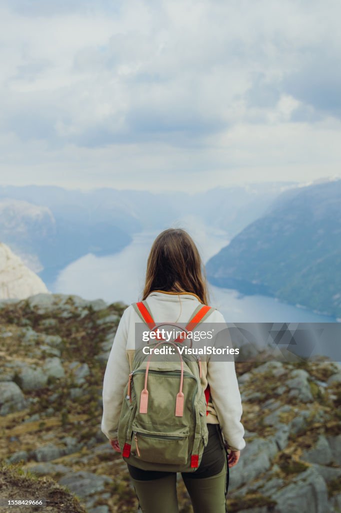 Glückliche Backpackerin bewundert den Blick auf den idyllischen Lysefjord von oben in Norwegen