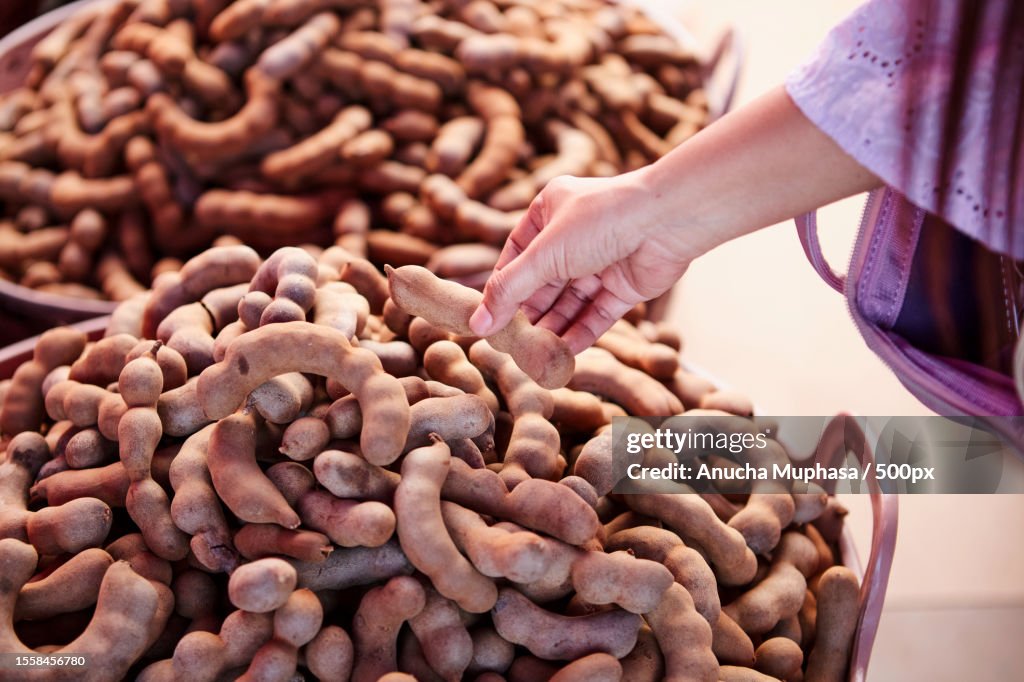 Midsection of woman buying Ripe sweet tamarind fruit at market stall,Phetchabun,Thailand
