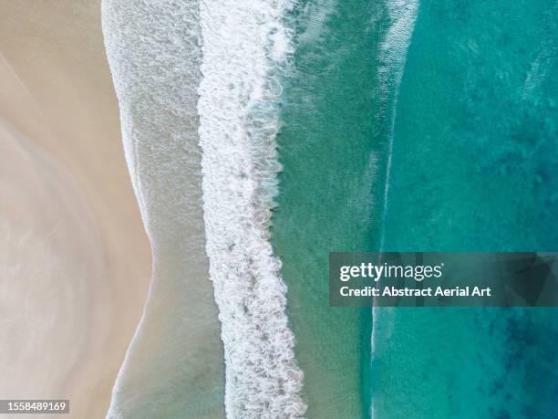 ocean waves crashing onto a beach in byron bay photographed from a drone point of view, new south wales, australia - byron bay stock-fotos und bilder