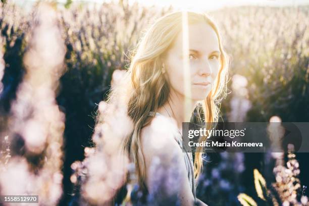 photo of a smiling young woman in lavender field; enjoying the beautiful and peaceful weekend getaway. - lavendel stock-fotos und bilder