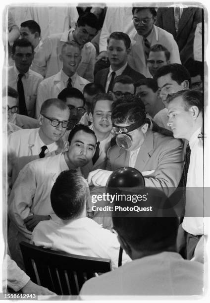 At Georgetown Medical School, students crowd around to watch a professor demonstrate exam techniques on a fellow student, Washington DC, April 1958.