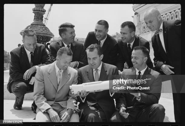 Vice President Richard M Nixon holds a model of a rocket as he sits, with the seven astronauts chosen for Project Mercury, on the steps of the East...