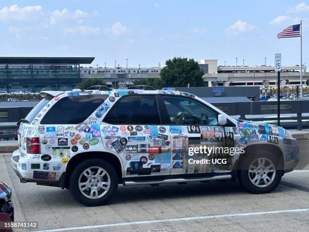 Car covered in bumper stickers outside Washington Dulles International Airport, Virginia.