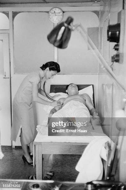 Chinese-born writer and physician Han Suyin attending to a patient, circa 1960.