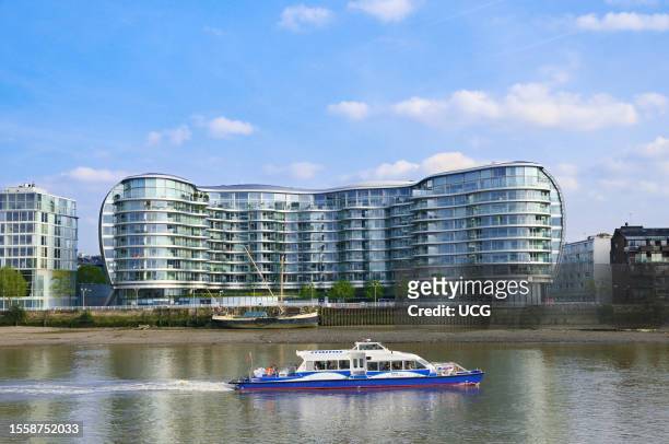 Thames Clipper boat passes the Albion Riverside building across the River Thames in Battersea in London. Architect: Foster and Partners.