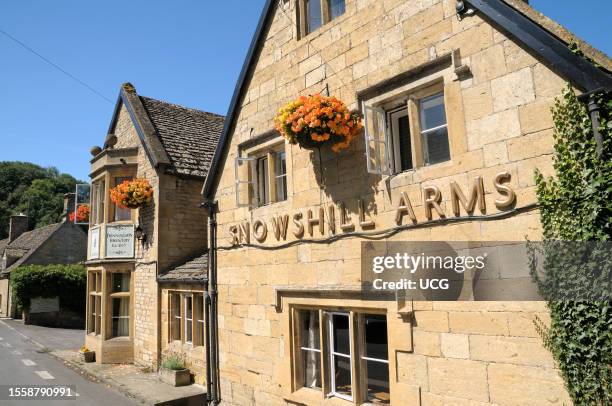 Traditional Cotswold stone exterior of the Snowshill Arms pub with summer hanging baskets in the picturesque village of Snowshill in the Cotswolds in...