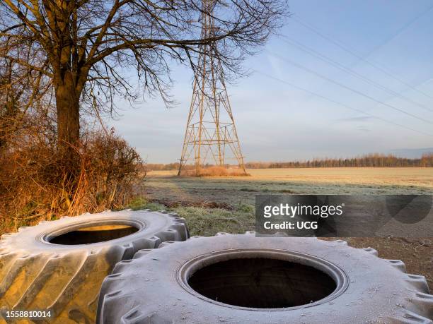 Electricity pylon in a field in Lower Radley Village, footpath blocked by giant tractor tires, winter sunrise.