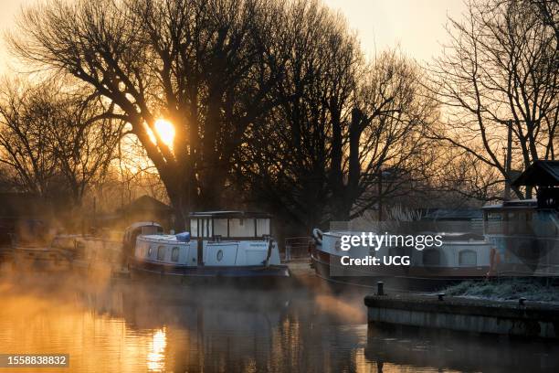 View from Abingdon Weir upstream of the River Thames, misty Autumn sunrise with houseboats.