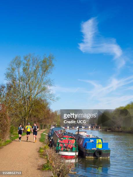Houseboats and joggers on the Thames in Oxford, early spring morning.