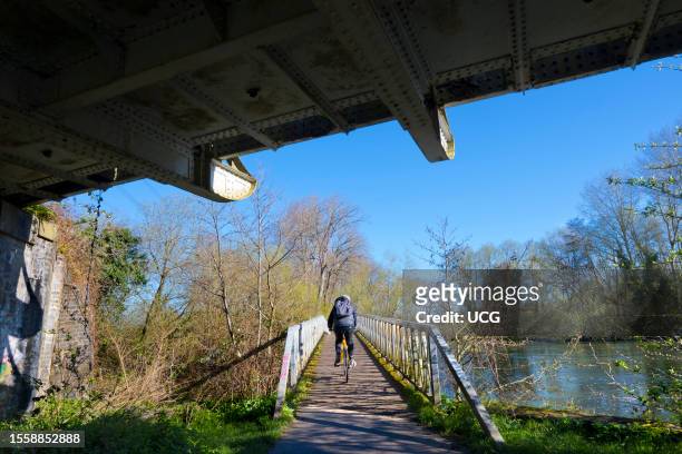 Jogger crossing a wooden footbridge over the Thames at Kennington, winter morning.