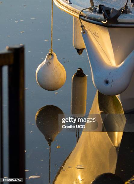 Buoys and reflections in the Thames, a small pleasure boat moored by the Thames at Abingdon on a fine Autumn morning.