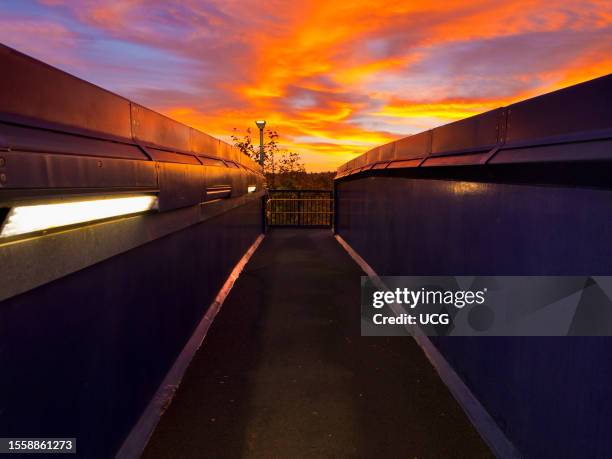 Elevated walkway over the tracks at Radley Railway Station, vivid Autumn pre-dawn.