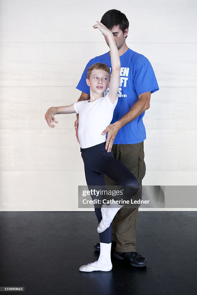 An instructor helping a young boy with ballet