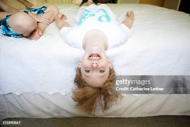 young girl upside down on bed - girl upside down stock pictures, royalty-free photos & images