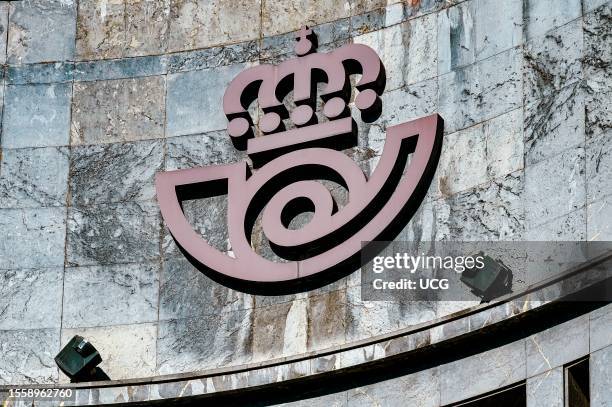 Oviedo, Asturias, Spain, Postal service or Correos sign. A weathered building wall with an embossed logo. The sign is illuminated by two electric...