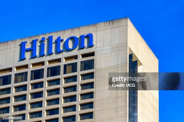 Toronto, Canada, The top portion of a building displaying a bold "Hilton" sign. The building has glass windows; no people are in the scene.