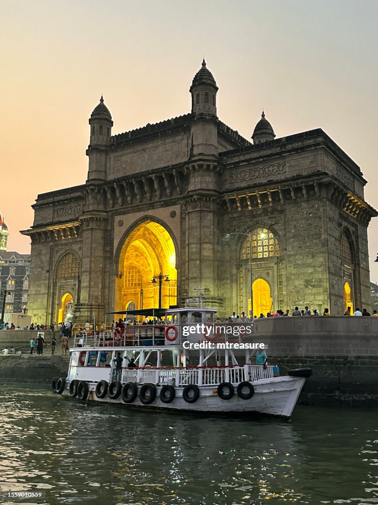 Nahaufnahme von Gateway of India, Mumbai, Indien, Blick auf das Fährterminal am Wasser, Passagierfähre in der Abenddämmerung, Fokus auf Vordergrund
