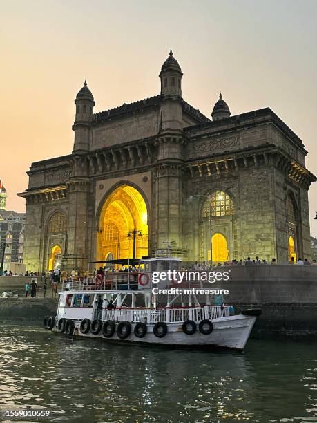 nahaufnahme von gateway of india, mumbai, indien, blick auf das fährterminal am wasser, passagierfähre in der abenddämmerung, fokus auf vordergrund - gateway to india stock-fotos und bilder