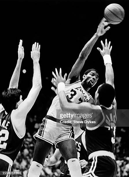 Earvin Magic Johnson of the Los Angeles Lakers passes the ball over Kevin McHale and Dennis Johnson of the Boston Celtics during an NBA Finals...
