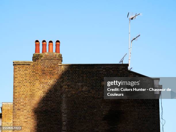 close-up of a shaded weathered brick gable with chimneys, rake antenna and blue sky in london, england, united kingdom - brick wall close up stock pictures, royalty-free photos & images