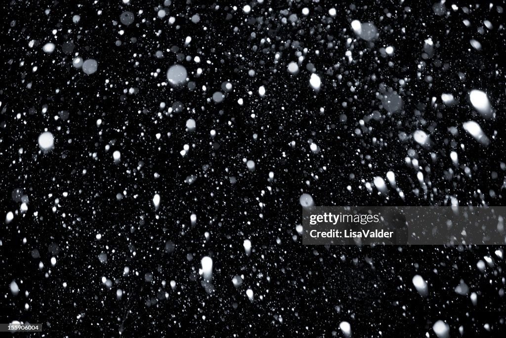 White snowflakes falling on a black background