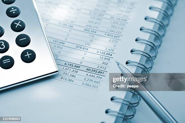 silver calculator and pen on sheet of financial data - accounting ledger stock pictures, royalty-free photos & images