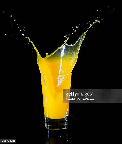 orange juice splashing in a glass - splash jus d'orange stockfoto's en -beelden