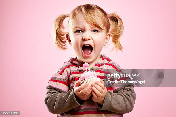 süße litte mädchen schmutzig lachen und hält rosa geburtstag cupcake - cupcakes girls stock-fotos und bilder