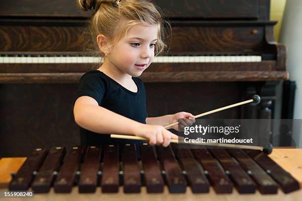 little girl playing xylophone with piano in background, horizontal. - xylophone stock pictures, royalty-free photos & images