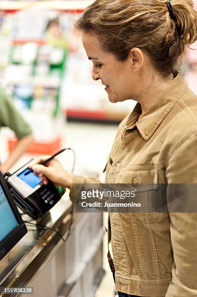 mature woman electronic signing her bill - 大賣場 個照片及圖片檔