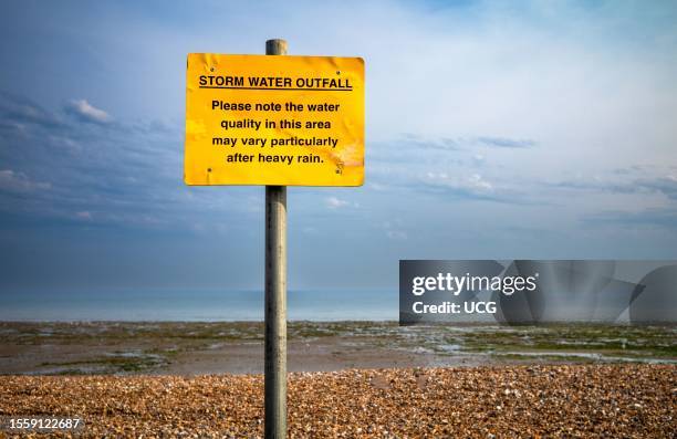 Sign warning people of the dangers from polluted water, especially after heavy rain, on the beach at Worthing, West Sussex, UK. Water companies in...