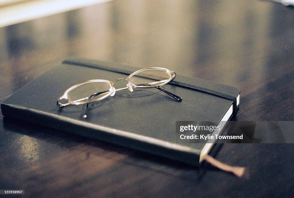 Diary with glasses on table