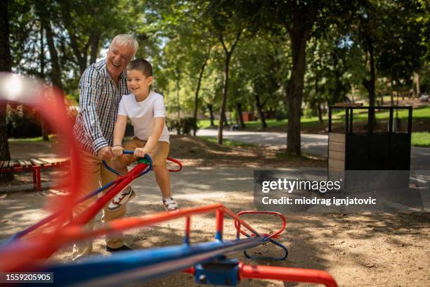 boy playing on seesaw - see saw stock pictures, royalty-free photos & images