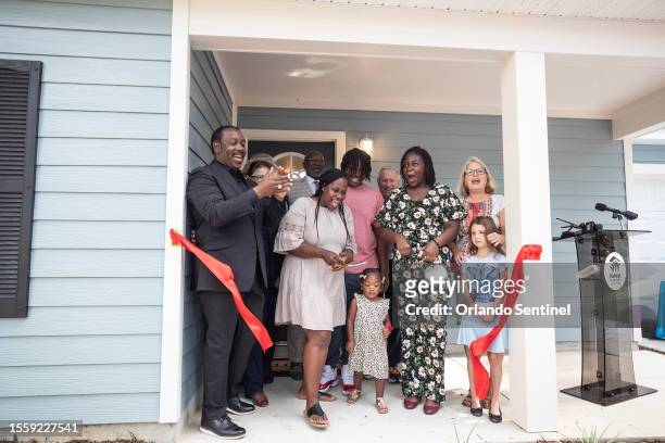 Keetonia Wilson, middle, cuts the red ribbon as her children, Orange County Mayor Jerry Demings, left, Apopka city officials and Habitat for Humanity...