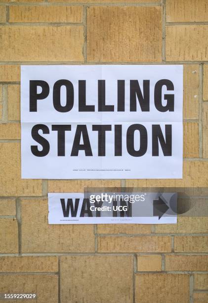 Sign reading "Polling Station" with the words "Way In" underneath fixed to a brick wall for elections in the UK. With a controversial new law...