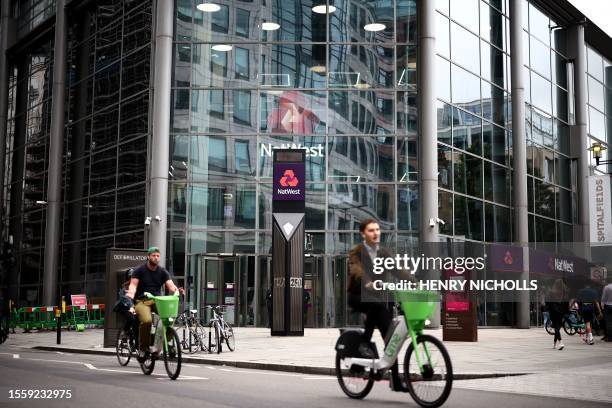 Cyclists ride e-bikes past the headquarters of NatWest bank in London on July 28, 2023. British bank NatWest said on Friday it had launched an...