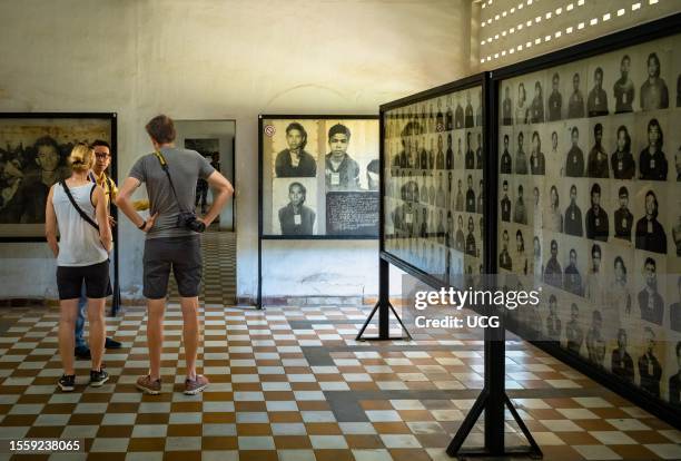Two western tourists with their tour guide in a room at the Tuol Sleng, or S-21, torture and genocide museum in Phnom Penh, Cambodia, containing...